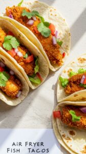 Recipe card for air fryer fish tacos next to a beautifully plated dish, with natural daylight highlighting both.